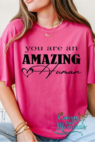 Pink "You Are An Amazing Human" tee with a heart detail, worn by a woman.