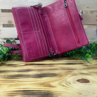 Open berry-colored clutch with white stitching, multiple card slots, and zippered pockets on a wooden surface.