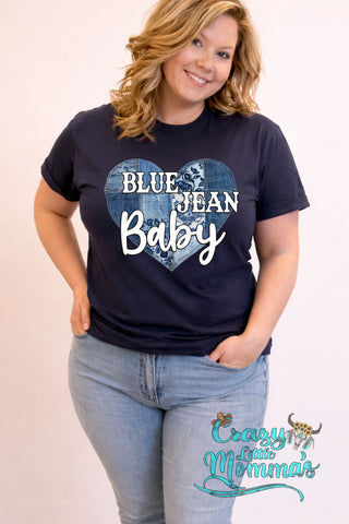 Woman wearing a navy Blue Jean Baby tee with a heart made of denim patches, paired with light wash jeans.