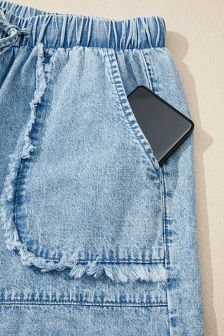 Close-up of light wash Canyon Frayed Hem Shorts with a phone in the distressed denim pocket.