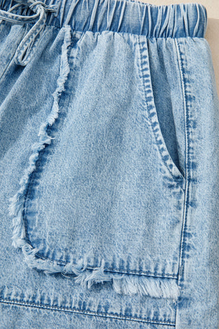 Close-up of light wash Canyon Frayed Hem Shorts with a drawstring waist and distressed denim pocket details.