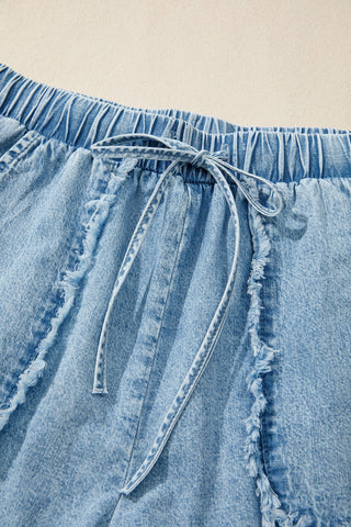 Close-up of light wash Canyon Frayed Hem Shorts with an elastic waist and tied drawstring.