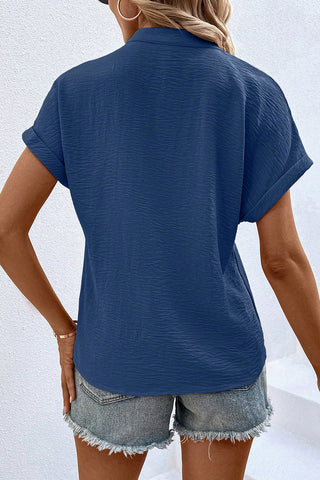 Back view of a woman wearing the blue Canyon Horizon Blouse with a crinkle texture and rolled short sleeves.