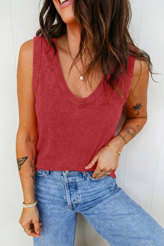 A woman wears a ribbed, faded red Canyon Sunset Tank with a V-neck, paired with light wash jeans.