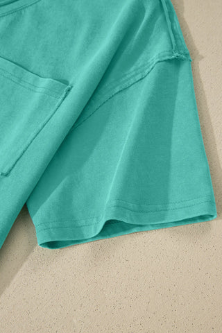 Close-up of a Canyon Teal Pocket Top, showing the washed teal fabric texture, pocket, and sleeve hem.
