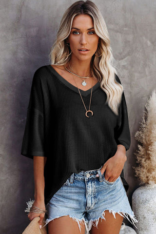 Woman wearing a black Canyon Waffle Knit Top with a V-neck and short sleeves, paired with denim shorts.