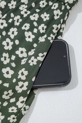Close-up of the Cloverfield Mini Dress pocket, holding a phone, showcasing the olive floral print.