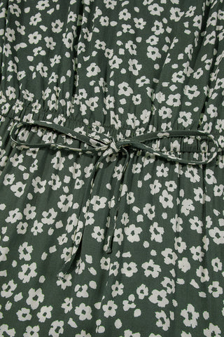 Close-up of an olive floral mini dress with a white floral pattern and a tied drawstring waist.