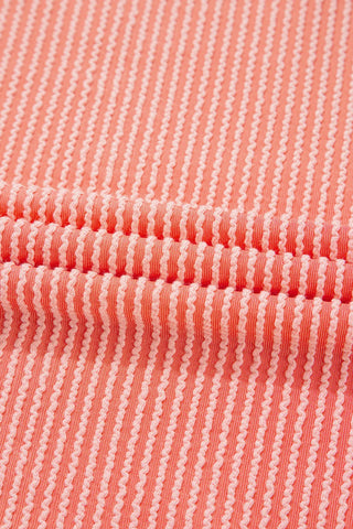 Close-up of the coral ribbed panel top fabric, showing vertical textured stripes in light and dark coral.