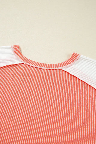 Close-up of a coral ribbed panel top with white ribbed panels on the shoulders and a ribbed neckline.