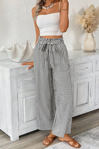 Woman wearing Cotton Field Striped Pants with a paperbag waist and tie, paired with a white crop top.