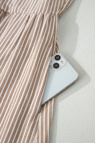 Close-up of a phone tucked into the pocket of the Daisy Lane Maxi Dress, showcasing the brown and white stripes.