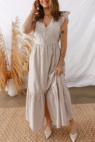 Woman in a Daisy Lane Maxi Dress, a boho striped maxi dress with ruffle sleeves and a button-down front.