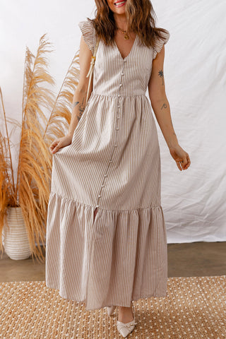Woman in a Daisy Lane Maxi Dress, a tan and white striped maxi dress with ruffle sleeves and button-front.