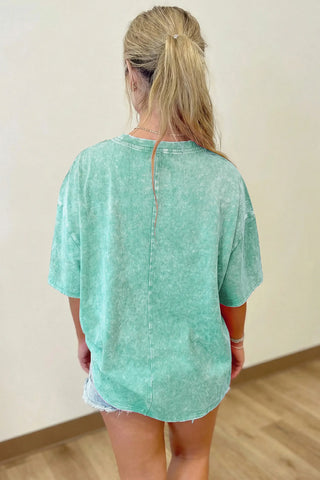 Back view of a woman wearing a Desert Sage Washed Tee, showcasing its vintage washed texture and relaxed fit.