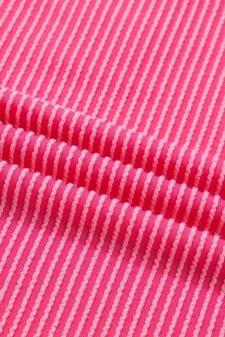 Close-up of the Desert Bloom Henley Top, showing its ribbed pink fabric with light pink wavy stripes.