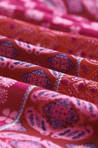 Close-up of the Desert Bloom Maxi Skirt, showing its vibrant red and pink bohemian patchwork pattern.