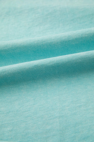 Close-up of the Desert Sky Raglan Tee fabric, showing its soft, washed teal color and ribbed texture.