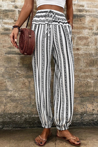 Woman wearing Desert Wanderer Striped Pants, white with black vertical stripes, drawstring waist, and elastic cuffs.