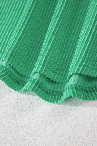Close-up of the vibrant green Desert Cat Ribbed Top, showing its textured fabric and wavy stripes.
