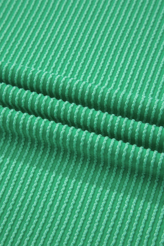 Close-up of the Desert Cat Ribbed Top fabric, showing its green color and textured wavy ribbed pattern.
