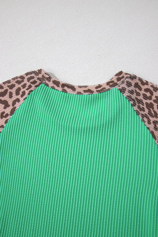 Close-up of a Desert Cat Ribbed Top with a green ribbed body and leopard print raglan sleeves.