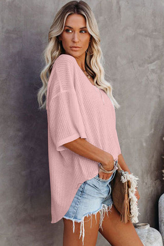 A blonde woman models a Desert Rose Waffle Top, a light pink waffle knit top with a relaxed fit.