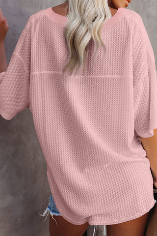 Back view of a woman wearing a loose-fitting Desert Rose Waffle Top, a light pink waffle knit top.