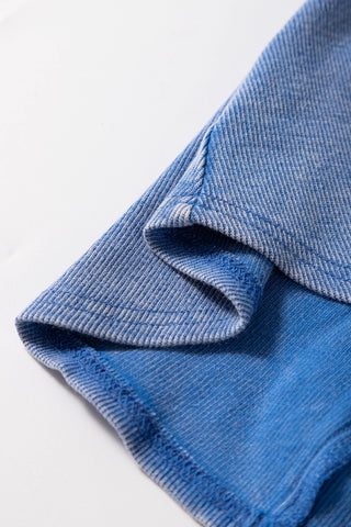 Close-up of the dusty blue ribbed Henley tank fabric, showing the texture and stitching.