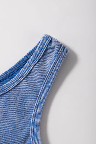 Close-up of a dusty blue ribbed Henley tank, showing the textured fabric and shoulder strap detail.