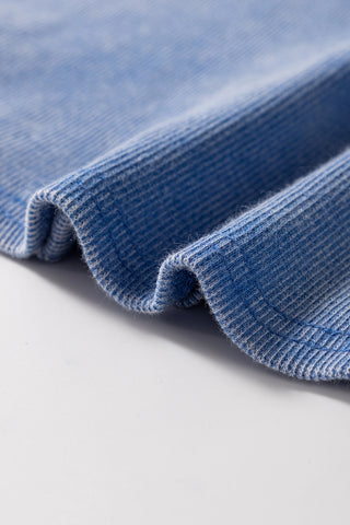 Close-up of the dusty blue ribbed Henley tank fabric, showing its soft texture and subtle variations in color.