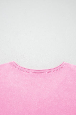 Close-up of the top of a dusty rose acid wash top, showing the rounded neckline and textured fabric.