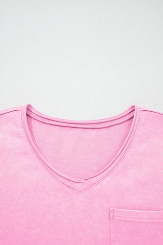 Close-up of a dusty rose acid wash V-neck top with a pocket on the lower right.