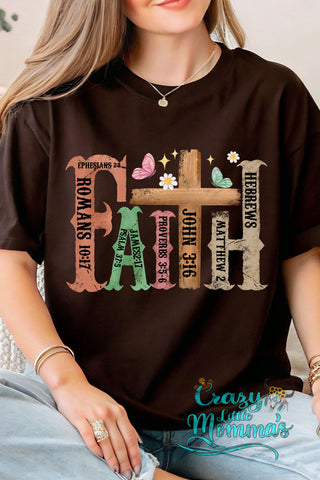 Woman wearing a dark brown rustic Faith shirt with colorful letters and Bible verses, butterflies, and flowers.