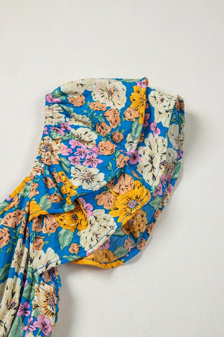 Close-up of a vibrant blue floral smocked jumpsuit with yellow, pink, and white flowers.