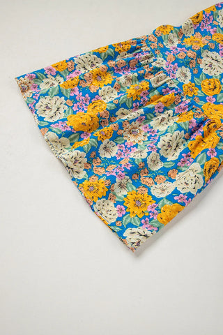 Close-up of a vibrant blue floral smocked jumpsuit with yellow, pink, and white flowers.