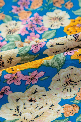 Close-up of the Canyon Bloom Jumpsuit fabric, showing a vibrant floral print on a blue background.