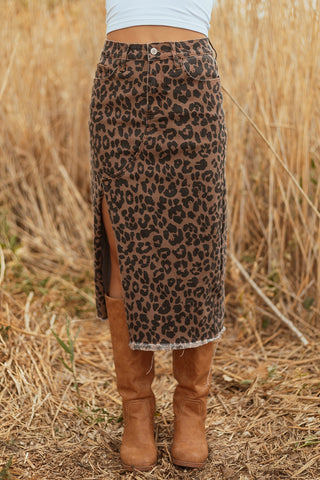 A model wears a leopard print denim skirt with a side slit and frayed hem, paired with brown boots.