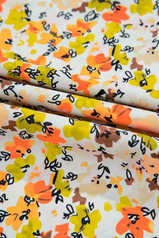 Close-up of the Meadow Blossom Flutter Top fabric, featuring a vibrant floral pattern with orange, yellow, and brown flowers.