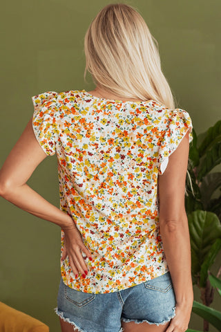 Back view of a woman wearing a vibrant floral flutter top with orange, yellow, and red flowers.