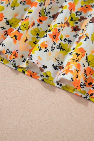 Close-up of the vibrant floral flutter top fabric, showing orange, yellow, and brown flowers on a white background.