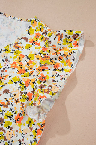 Close-up of a vibrant floral flutter top with orange, yellow, and brown flowers on a white background.