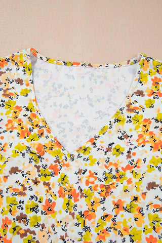 Close-up of a vibrant floral flutter top with a V-neckline, featuring yellow, orange, and brown flowers.