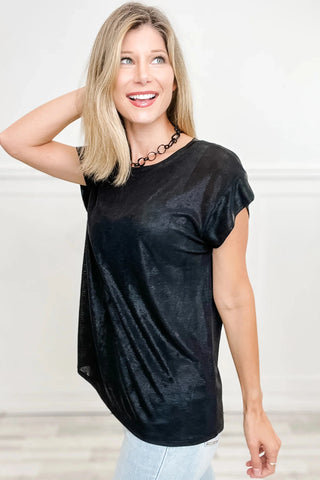 Blonde woman smiling, wearing a black shimmer draped blouse with a black chain necklace.