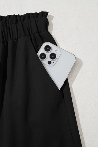 Close-up of Midnight Prairie Wide Pants pocket holding a smartphone, highlighting the relaxed black palazzo pants.