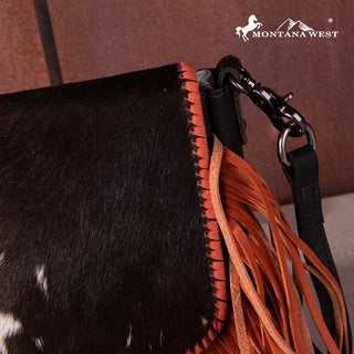 Close-up of a Montana West cowhide fringe crossbody purse with black and white fur and orange fringe.
