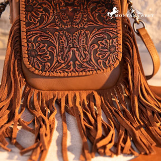 Close-up of a brown leather crossbody purse with intricate floral tooling and long fringe details.