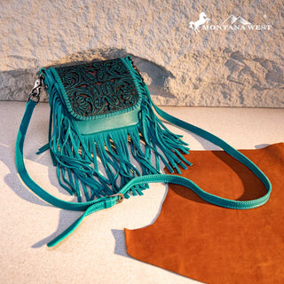 Turquoise Montana West crossbody purse with a tooled leather flap and long fringe, on a light background.