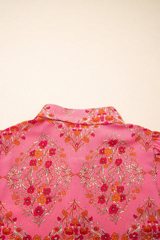 Close-up of a vibrant floral geometric blouse in pink, orange, and white with a collared neckline.