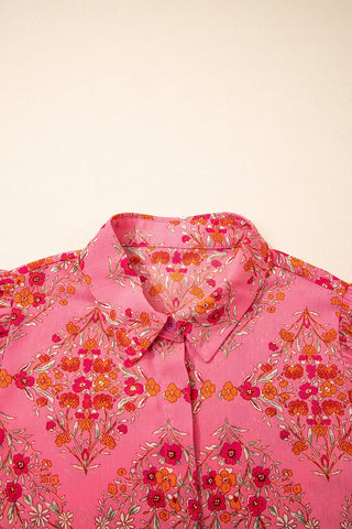 Close-up of a vibrant floral geometric blouse in pink with orange and red flowers, featuring a collar.